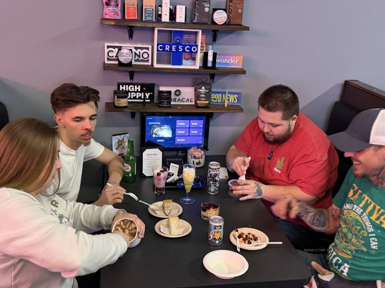 Group of 4 people shown at booth enjoying Smoke Lab drinks and snacks.
